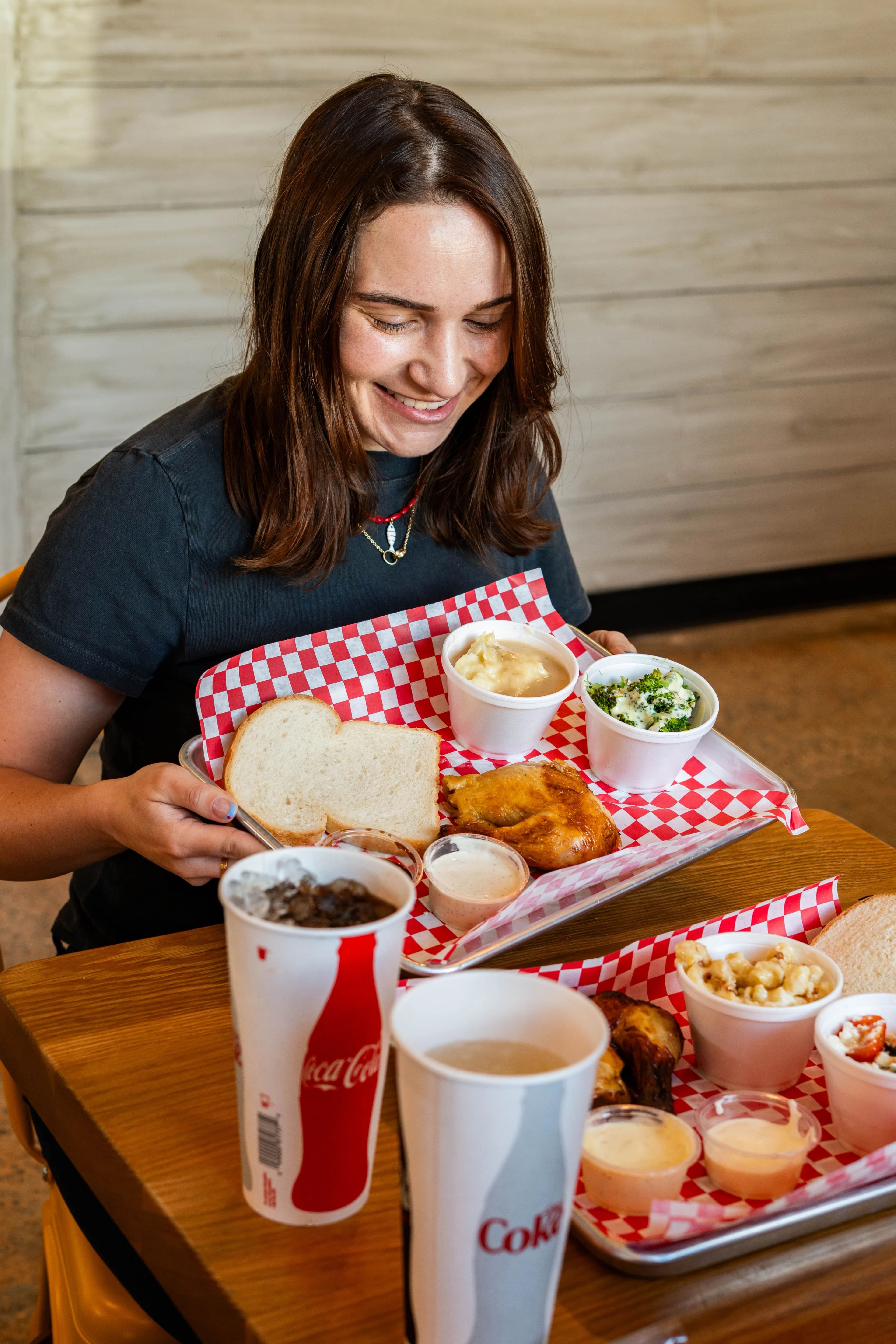 Guest smiling while holding a tray of rotisserie chicken and sides