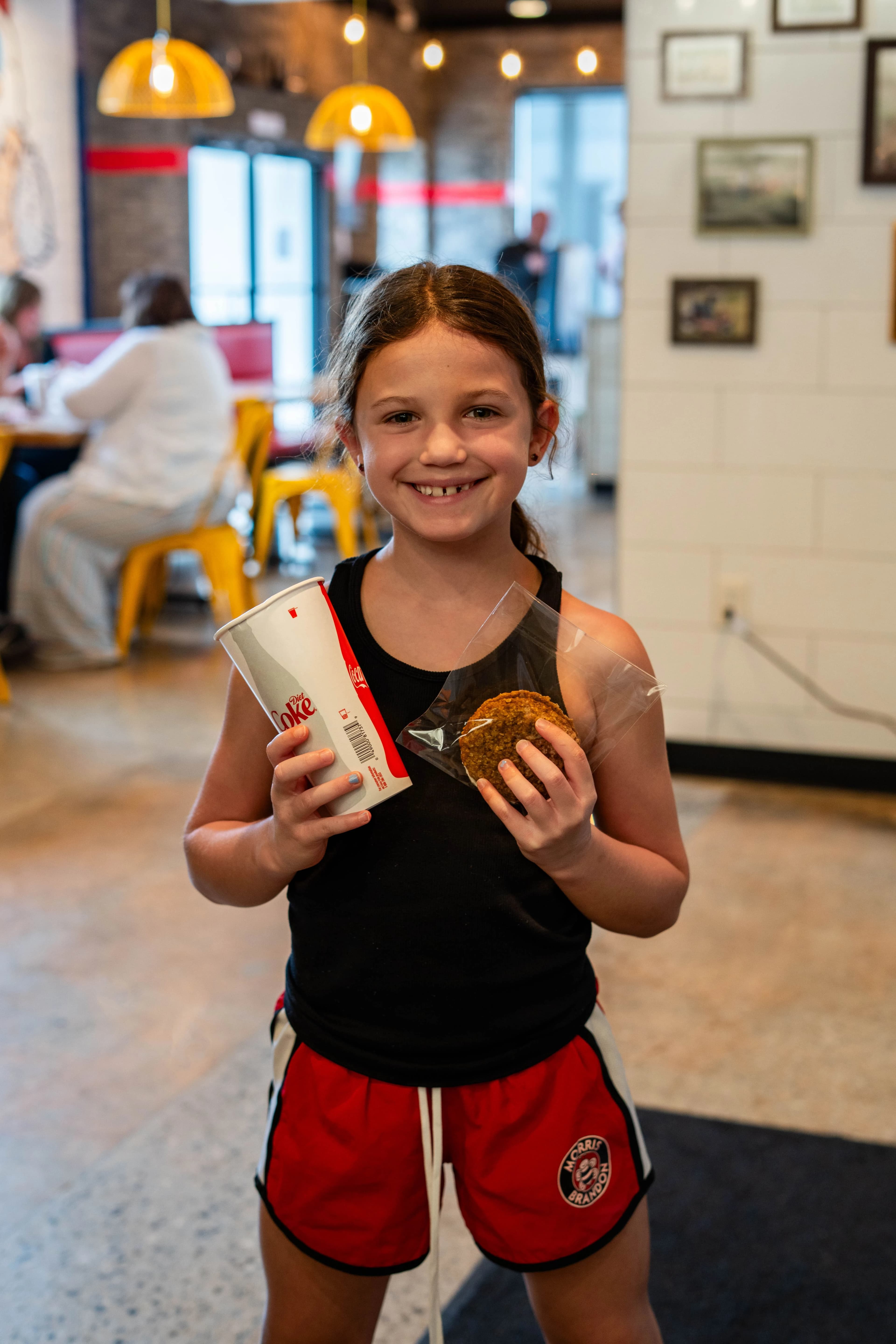 Child holding a drink and a cookie at Pretty Hens