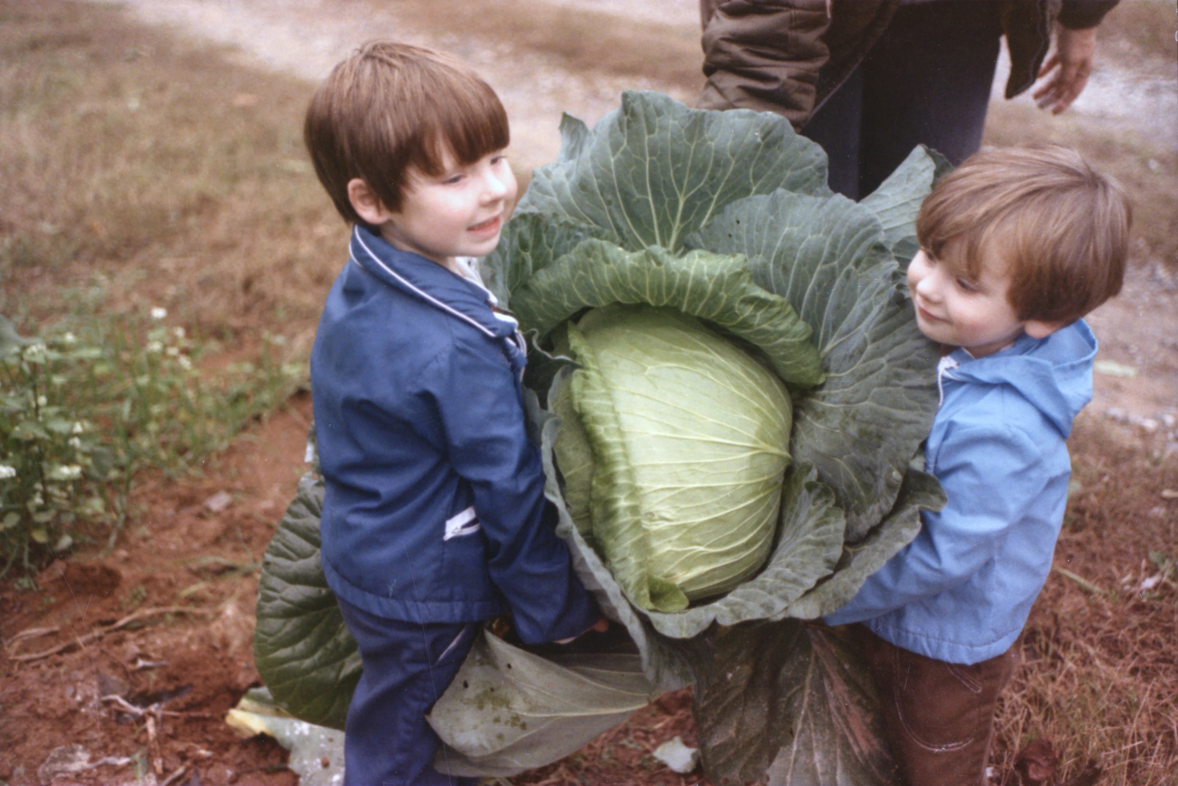 Childhood photo of two Pretty Hens founders holding a large cabbage from the family farm